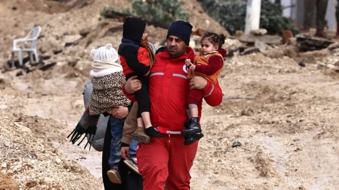 Membro do Crescente Vermelho ajuda família palestina a deixar casa no campo de refugiados de Nur Shams, perto de Tulkarm, durante ataque israelense em 10/2/ 2025 (AFP/Zain Jaafar)