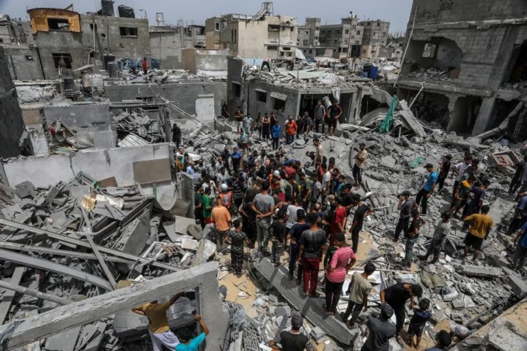 Moradores e equipes de defesa civil realizam operações de busca e resgate entre os escombros de prédios destruídos após ataque de Israel ao campo de refugiados de Khan Yuni, em 1º de julho de 2025 (Abed Rahim Khatib – Agência Anadolu)