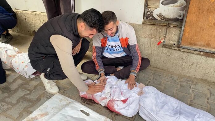 Jovens choram sobre o corpo de parente morta em frente ao hospital Al-Awda, em Gaza, após ataques aéreos de Israel em 29/10 (captura de tela de vídeo gravado por Abdel Qader Sabbah)