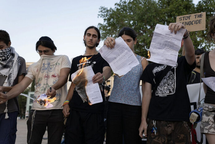 Jovens israelenses queimam seus avisos de convocação militar em protesto contra o genocídio em Gaza - Tel Aviv, 15/7/2025 (foto: Oren Ziv)