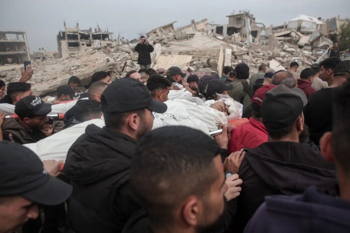 Palestinos que perderam familiares em ataque israelense durante o funeral realizado em frente às suas casas no bairro de Rimal, em Gaza, em 15 de abril (foto de Abdalhkem Abu Riash/Anadolu)