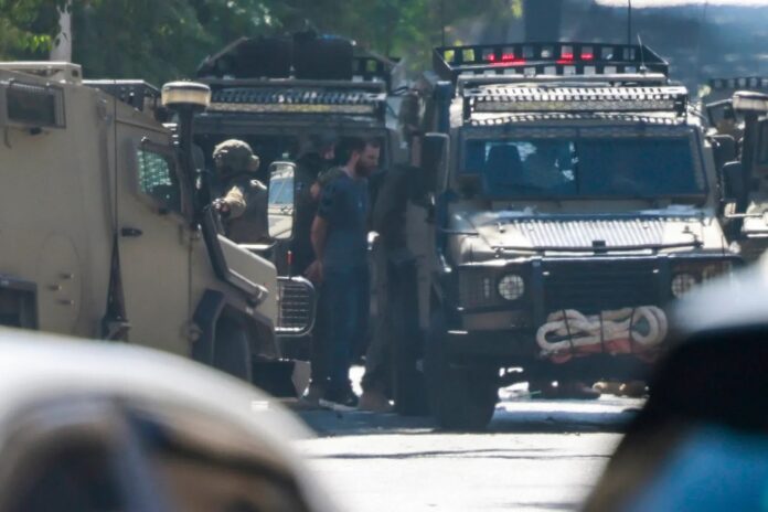 Soldados israelenses prendem palestino no Hospital de Nablus, na Cisjordânia Ocupada (foto: Jaafar Ashtiyeh/AFP)