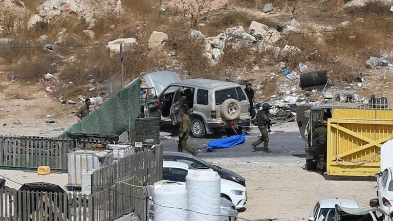 Militares de Israel ao lado do corpo de Hossam Abdul Walid Ali (no saco azul), palestino morto a tiros em Hebron (foto: Anadolu)